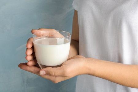 Woman holding glass of hemp milk on light blue background, closeupの写真素材