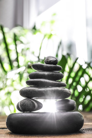 Table with stack of stones and blurred green leaves on background. Zen conceptの写真素材