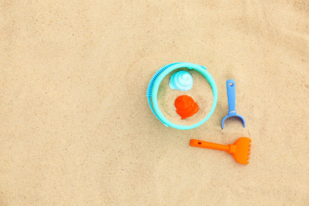 Set of plastic beach toys on sand, top view. Space for text