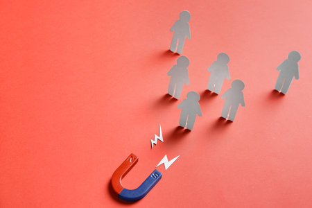 Magnet attracting paper people on red background, space for text. business rivalry conceptの写真素材