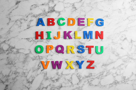 Colorful magnetic letters on white marble background, flat lay. alphabetical orderの写真素材