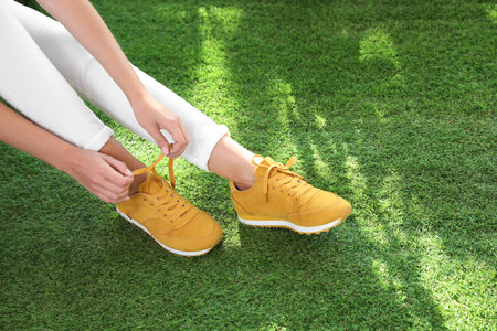 Young woman wearing stylish sneakers on green grass, closeupの写真素材