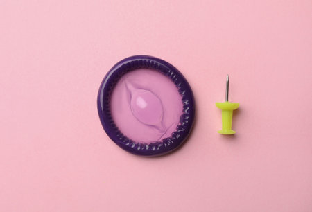 Purple condom and pin on pink background, flat layの写真素材