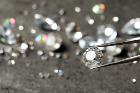 Tweezers with beautiful gemstone on blurred background. Space for text