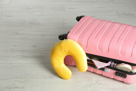 Suitcase with clothes and travel pillow on wooden floorの写真素材