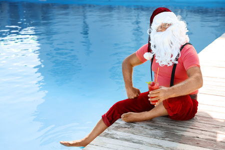 Authentic Santa Claus with cocktail near pool at resortの写真素材