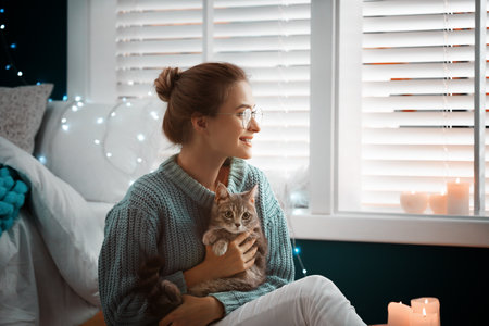 Young woman with cute cat at home. Cozy winter
