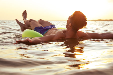 Young man with inflatable ring in the seaの写真素材