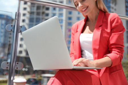 Businesswoman using laptop on city street, closeupの写真素材