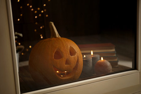 Composition with pumpkin head on windowsill, view through glass. Jack lantern - traditional Halloween decorの写真素材