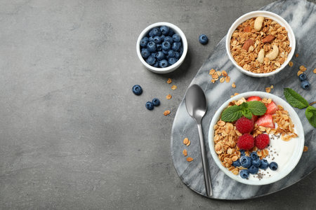 Healthy homemade granola with yogurt on gray table, flat lay. Space for textの写真素材