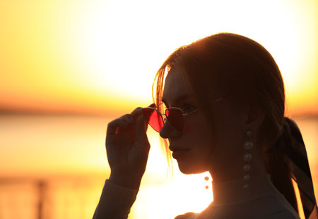 Silhouette of a young woman outdoors at sunsetの写真素材