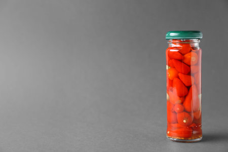 Jar of pickled red hot piri-piri peppers on gray background. Space for textの写真素材
