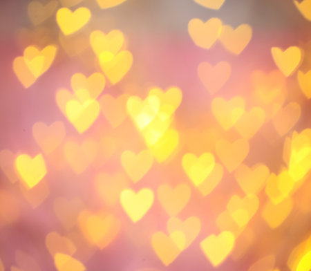 Blurred view of gold heart shaped lights on pink backgroundの写真素材