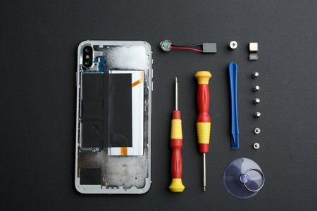 Disassembled mobile phone and repair tools on black background, flat layの写真素材
