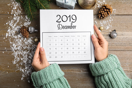 Woman with paper calendar at wooden table, top viewの写真素材