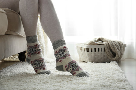Woman wearing knitted socks at home, closeup. warm clothes