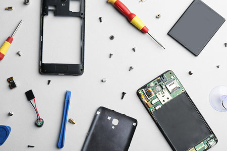Disassembled mobile phone and repair tools on light background, flat layの写真素材