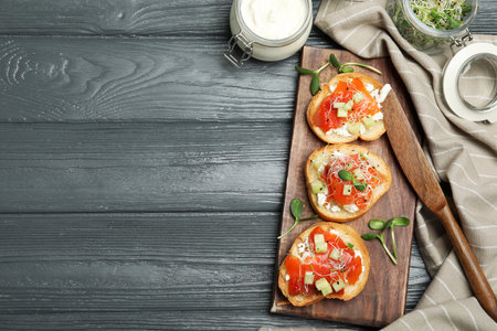 Flat lay composition of tasty bruschettas with salmon on dark gray wooden table. Space for textの写真素材