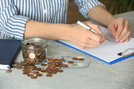 Woman counting coins at table, closeup. money savings