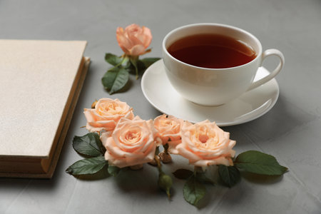 Hardcover book, flowers and cup of tea on gray tableの写真素材