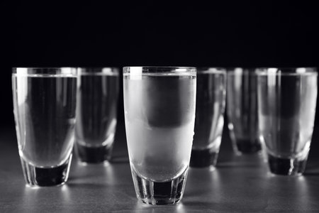Shots of vodka on gray table against black backgroundの写真素材