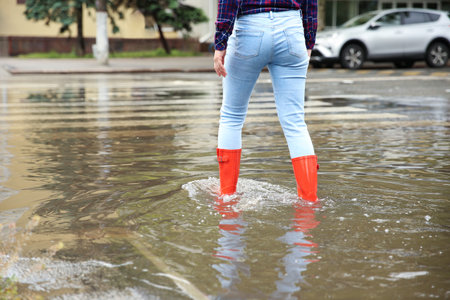 Woman with red rubber boots in puddle, closeup. rainy weatherの写真素材