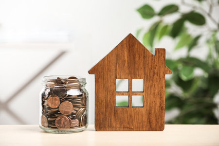 House model and glass jar with coins on table. money savingsの写真素材
