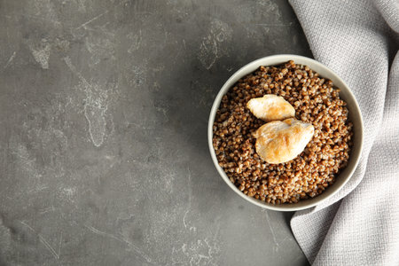 Tasty buckwheat porridge with meat on gray table, top view. Space for textの写真素材