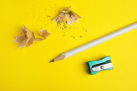 Pencil, sharpener and shavings on yellow background, flat layの写真素材