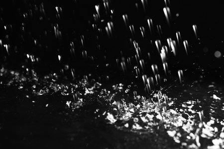 Heavy rain falling down on ground against dark background, closeupの写真素材