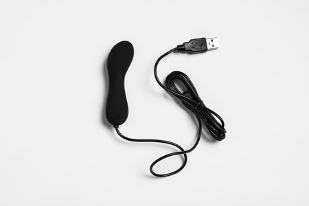 Black vibrator on white background, top view. sex toy