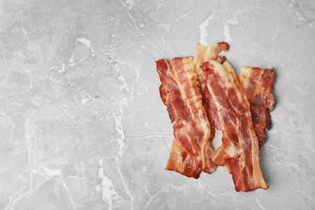 Slices of tasty fried bacon on light gray marble table, top view. Space for textの写真素材