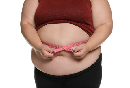 Overweight woman measuring waist with tape on white background, closeupの写真素材
