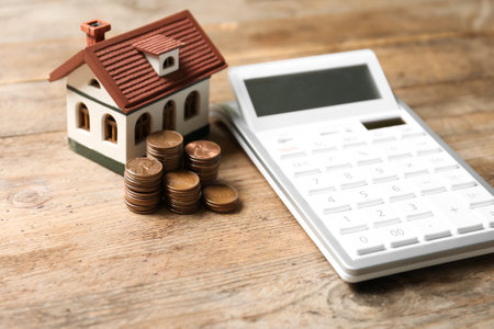 House model with coins and calculator on wooden table. real estate agent serviceの写真素材