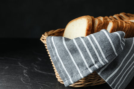 Slices of bread in basket on table against black backgroundの写真素材