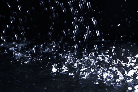 Heavy rain falling down on ground against dark background, closeupの写真素材