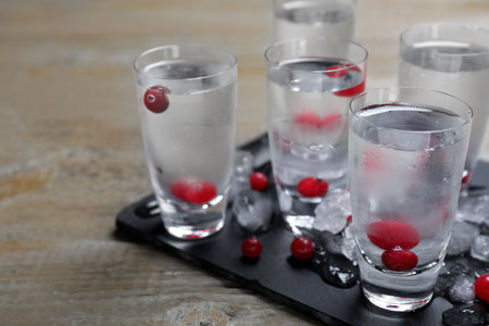 Shots of vodka, ice and cranberries on wooden tableの写真素材