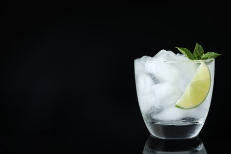 Glass of cocktail with vodka, ice and lime on black background. Space for textの写真素材