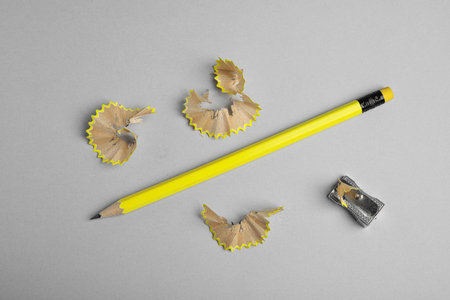 Pencil, sharpener and shavings on gray background, flat lay