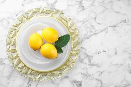 Fresh lemons and leaves on white marble table, top view. Space for tableの写真素材