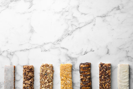 Healthy granola bars on white marble table, flat lay. Space for textの写真素材