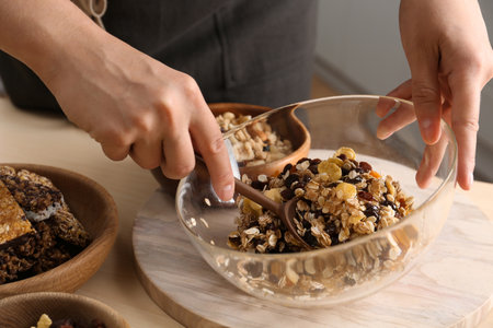 Woman preparing healthy granola bar at wooden table, closeup