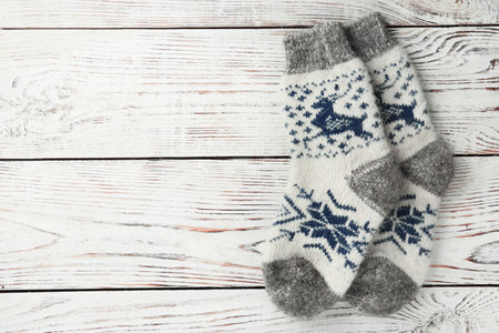 Warm knitted socks on white wooden background, flat lay. Space for text