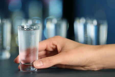 Woman with shot of vodka at table in bar, closeupの写真素材