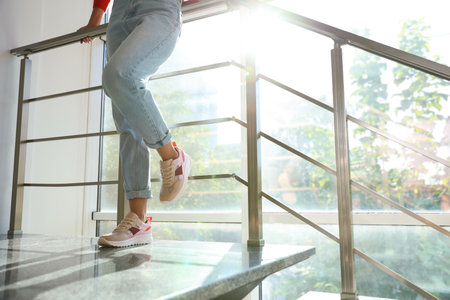 Young woman wearing stylish sneakers on staircase indoors, closeupの写真素材