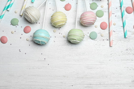Flat lay composition with sweet cake pops on white wooden background. Space for textの写真素材