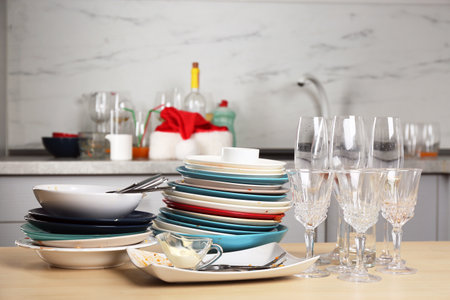 Dirty dishes and glasses on wooden table in kitchen after party