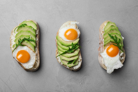 Delicious avocado sandwiches on gray table, flat layの写真素材