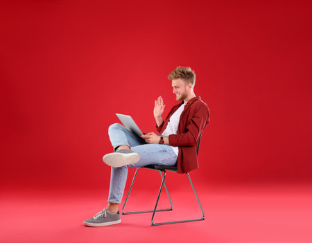 Happy man with laptop on red backgroundの写真素材